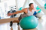 Man Balancing On Swiss Ball At Gym