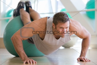 Man Balancing On Swiss Ball At Gym