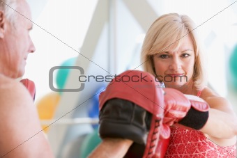 Woman Boxing With Personal Trainer At Gym