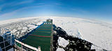 Panoramic shot of a ship navigating in ice.