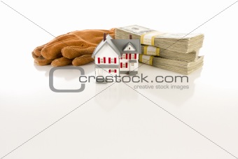 Stacks of One Hundred Dollar Bills, Leather Work Gloves and Small House on Slight Reflective Surface.