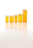 Several Different Sized Empty Medicine Bottles as Increasing Graph on Reflective Surface.