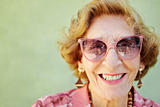 aged woman with pink eyeglasses smiling at camera