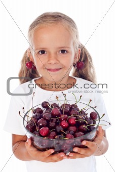 Little girl with cherry earrings holding a bowl of fresh fruits