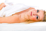 Portrait of sensual young girl with blonde hair and expressive eyes lying on bed
