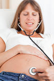Facing view of a beautiful pregnant woman using a stethoscope wh