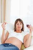 Beautiful pregnant woman holding a cigarette and a glass of red wine