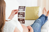 Beautiful pregnant woman looking at a sonograph