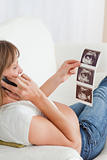 Beautiful pregnant woman on the phone and looking at an ultrasound