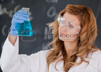 Beautiful female scientist looking at a flask