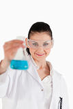 Dark-haired scientist with safety glasses holding a blue flask