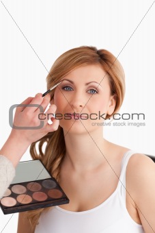 Make-up artist applying make up to a blond-haired female