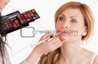 Cute woman having her make up done by a make up artist