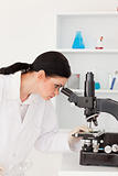 Dark-haired female scientist looking through a microscope