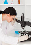 Dark-haired female looking through a microscope