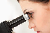 Dark-haired scientist looking through a microscope