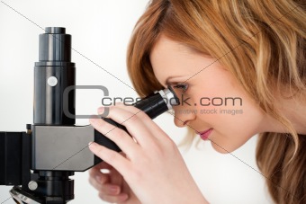 Blond-haired scientist looking through a microscope