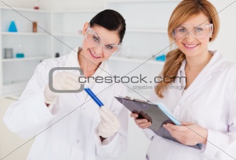 Two scientists looking at the camera while holding a test tube a