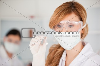 Blond-haired scientist wearing a mask and safety glasses and hol