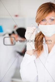 Cute scientist woman holding a test tube looking at the camera