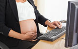 Young pregnant woman on the phone working with a computer