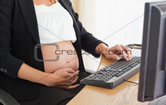 Young pregnant woman on the phone working with a computer