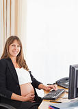 Attractive pregnant woman working with a computer