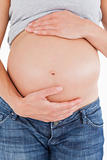 Close-up of a pregnant woman caressing her belly while standing