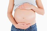 Close-up of a young pregnant woman caressing her belly while sta