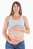 Beautiful pregnant woman caressing her belly while standing