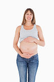 Attractive pregnant woman caressing her belly while standing