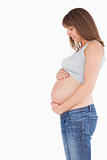 Side view of an attractive pregnant woman caressing her belly wh