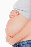 Side view of a pregnant woman caressing her belly while standing