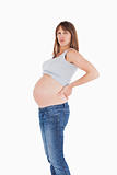 Beautiful pregnant woman holding her back while standing