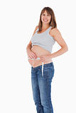 Good loooking pregnant woman measuring her belly while standing