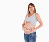 Pretty pregnant woman measuring her belly while standing