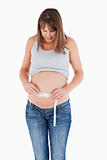 Lovely pregnant woman measuring her belly while standing