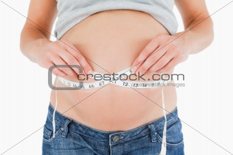 Young pregnant woman measuring her belly while standing
