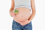 Pregnant woman holding a broccoli while standing