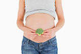 Young pregnant woman holding a broccoli while standing