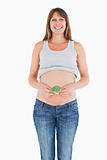 Beautiful pregnant woman holding a broccoli while standing