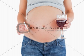 Pregnant woman holding a glass of red wine while standing