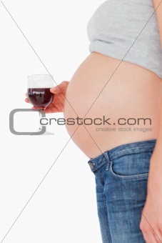 View profile of a young pregnant woman holding a glass of red wi