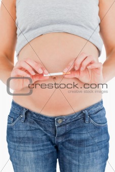 Young pregnant woman holding a cigarette while standing