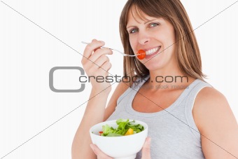 Good looking pregnant woman eating a cherry tomato while holding