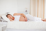 Beautiful pregnant woman relaxing while lying on her bed