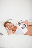 Beautiful pregnant woman holding an ultrasound scan while lying 