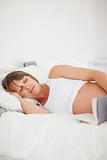 Good looking pregnant woman reading a book while lying on her be