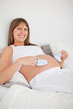Charming pregnant woman playing with little socks while lying on