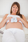 Gorgeous pregnant woman playing with little socks while lying on
